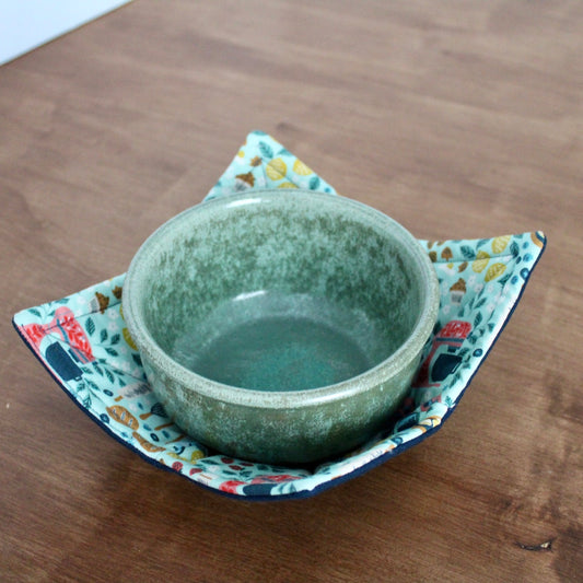 Green ceramic bowl on a floral fabric coaster on a wooden surface